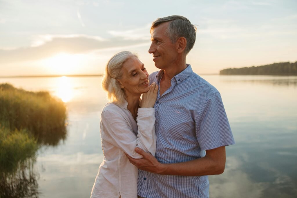 Why Moving to Florida is the Best Decision You Can Make A senior couple lovingly embraces by a serene lake during a beautiful sunset.